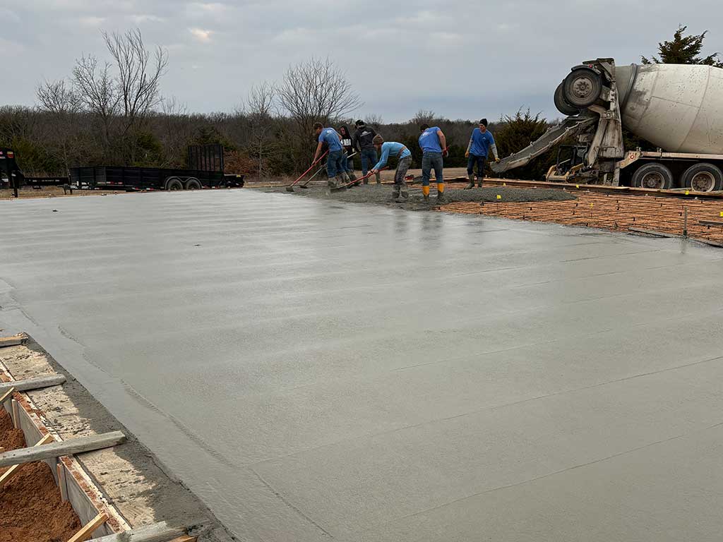 Rodgers concrete crew, pouring out and screening concrete shop slab.